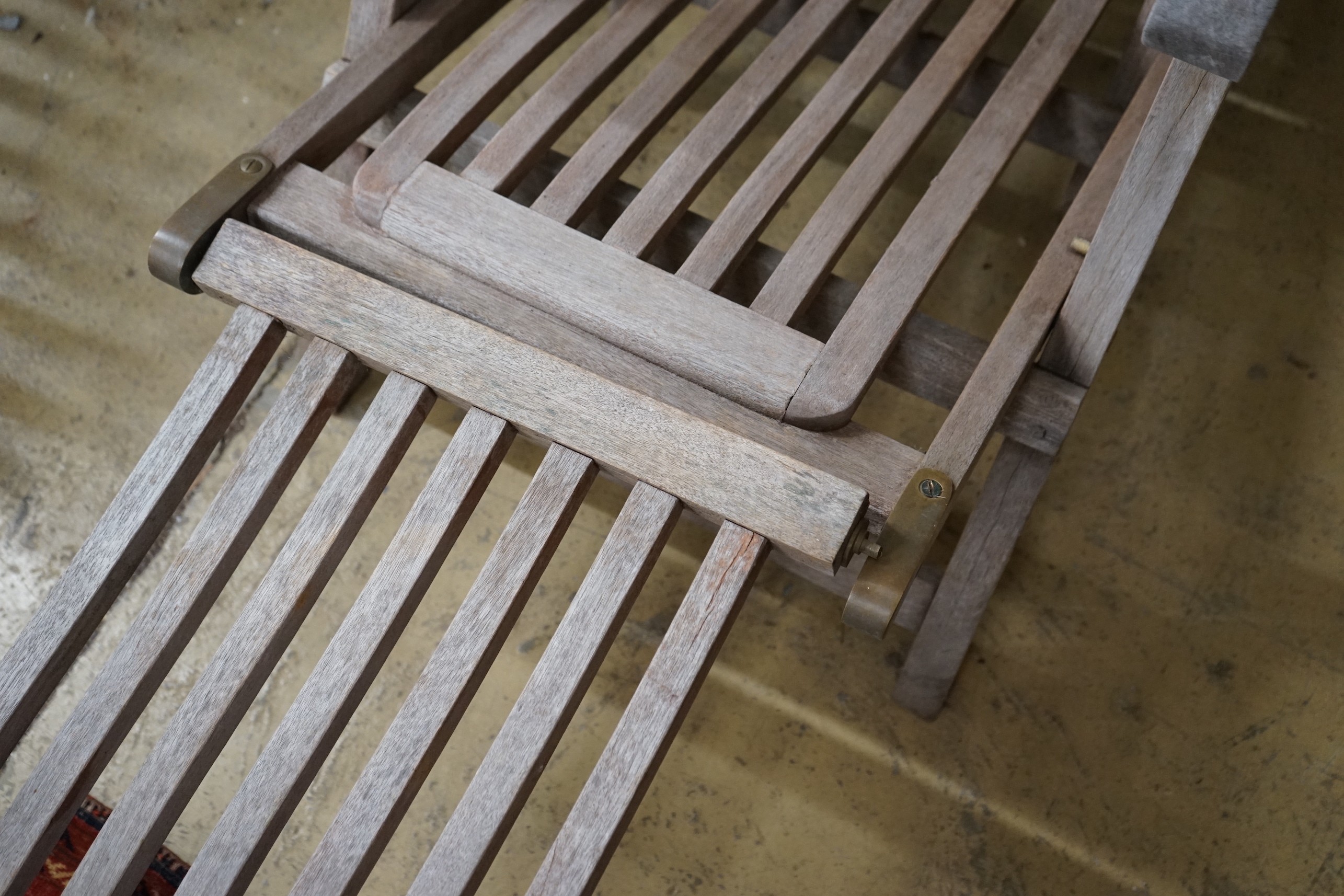 A weathered teak garden steamer chair with brass fittings